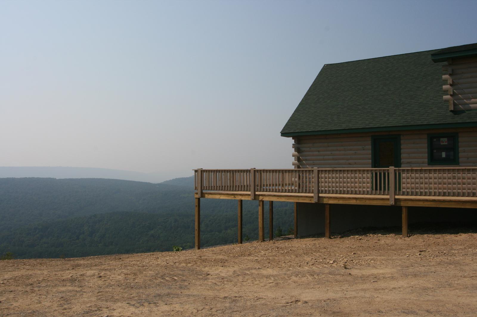 A deck on tall posts reaching out toward a valley, the roofline of the house closing the frame