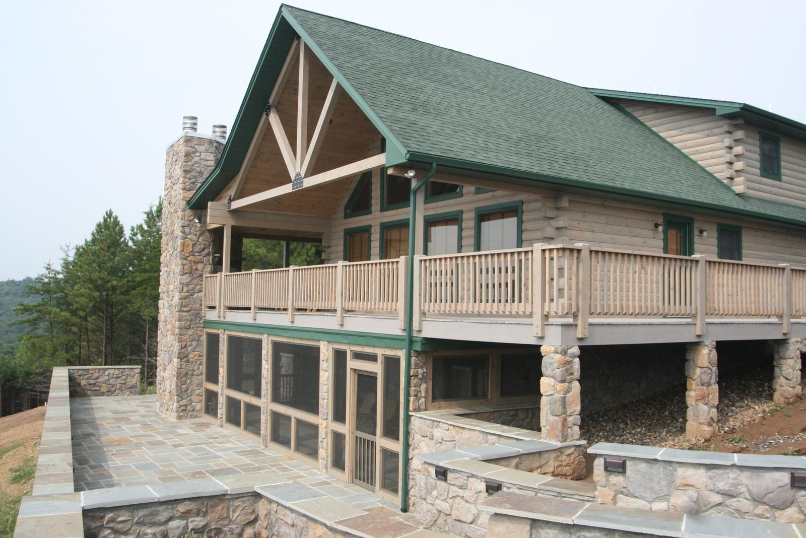 The house from the terrace corner, timber truss in the gable above the deck and stone running up the chimney