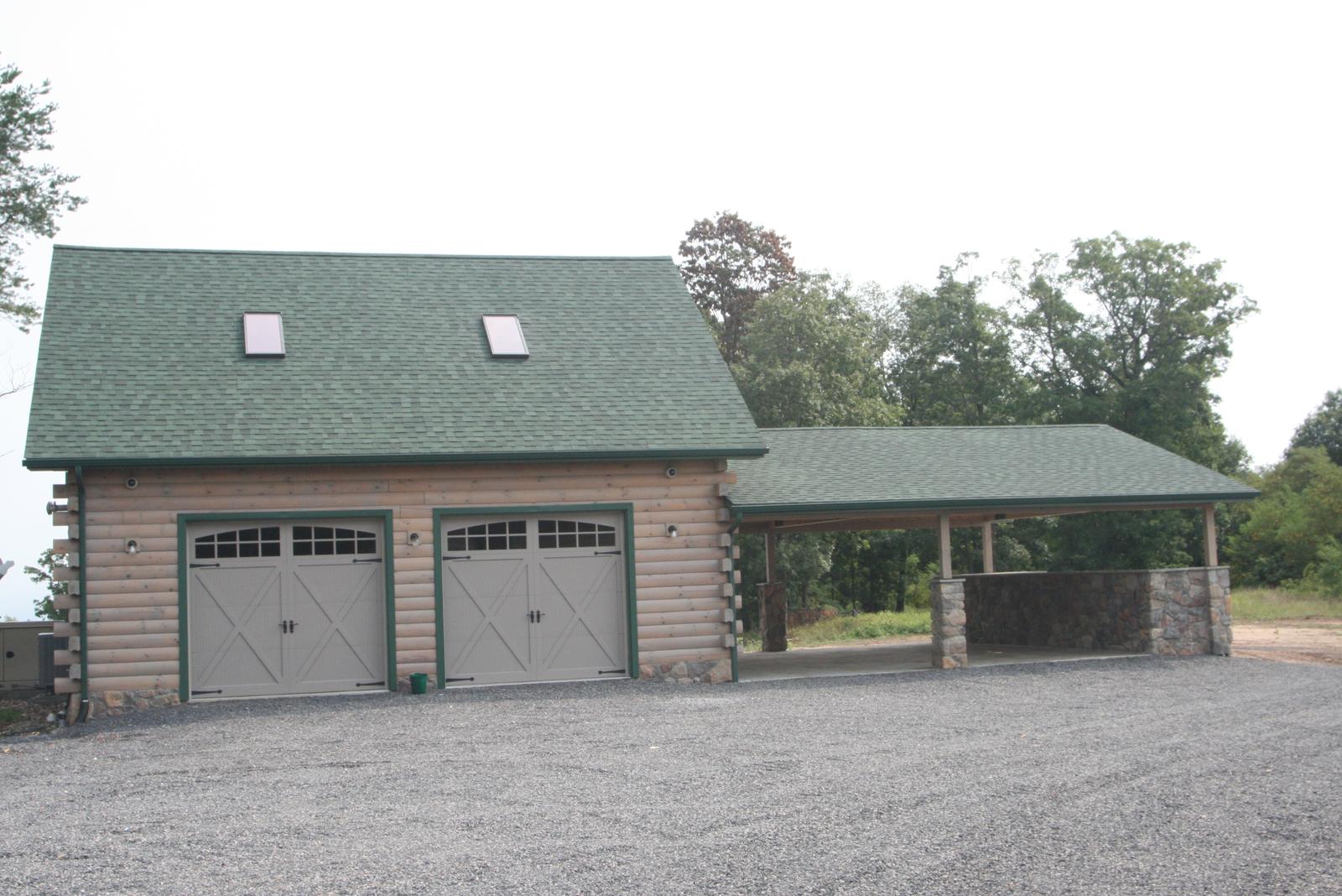 A detached garage with two carriage doors and roof skylights, a covered bay beside it on stone piers