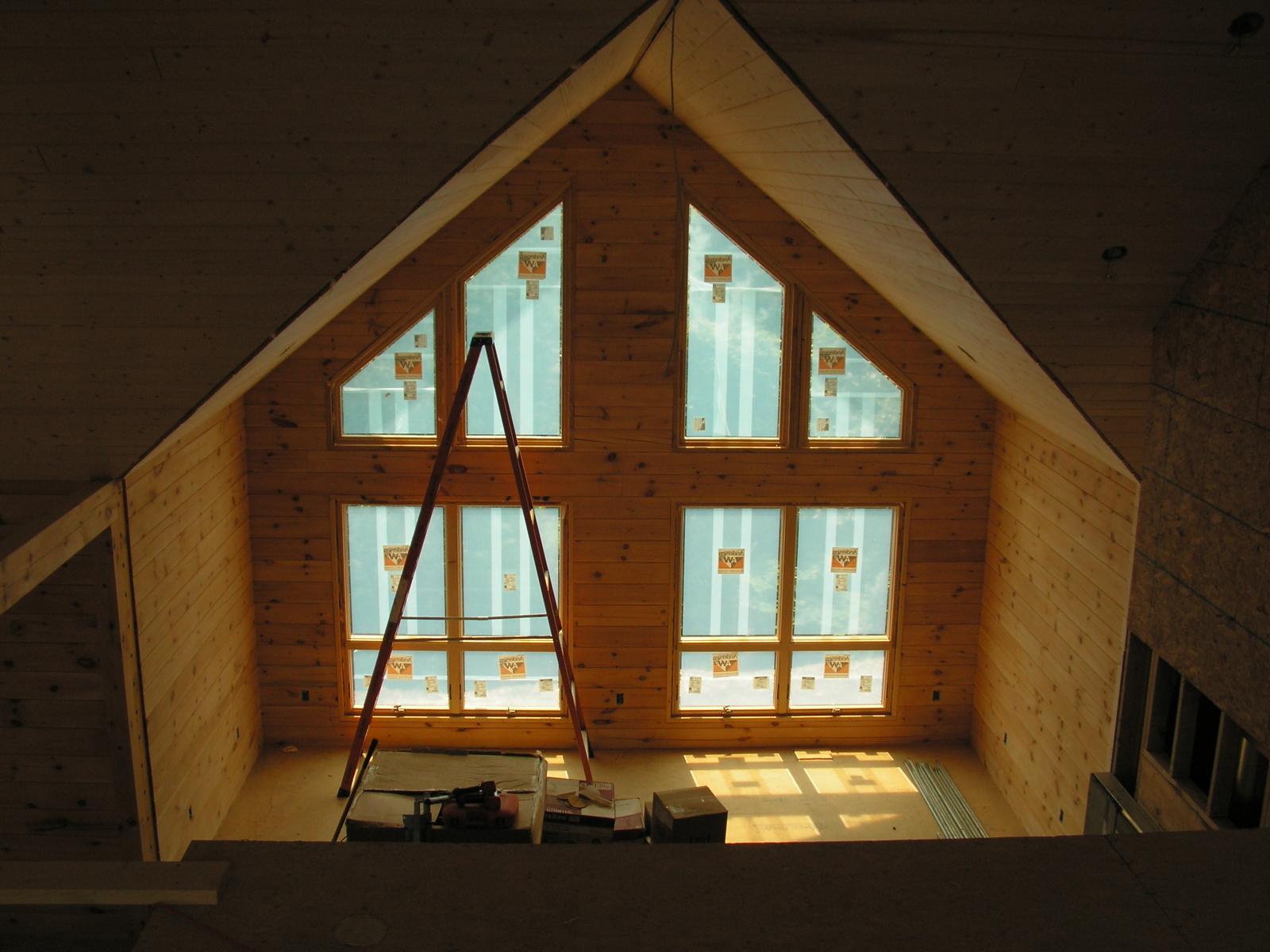 A gable wall of windows seen from inside, a stepladder standing against it and stickers still on the glass