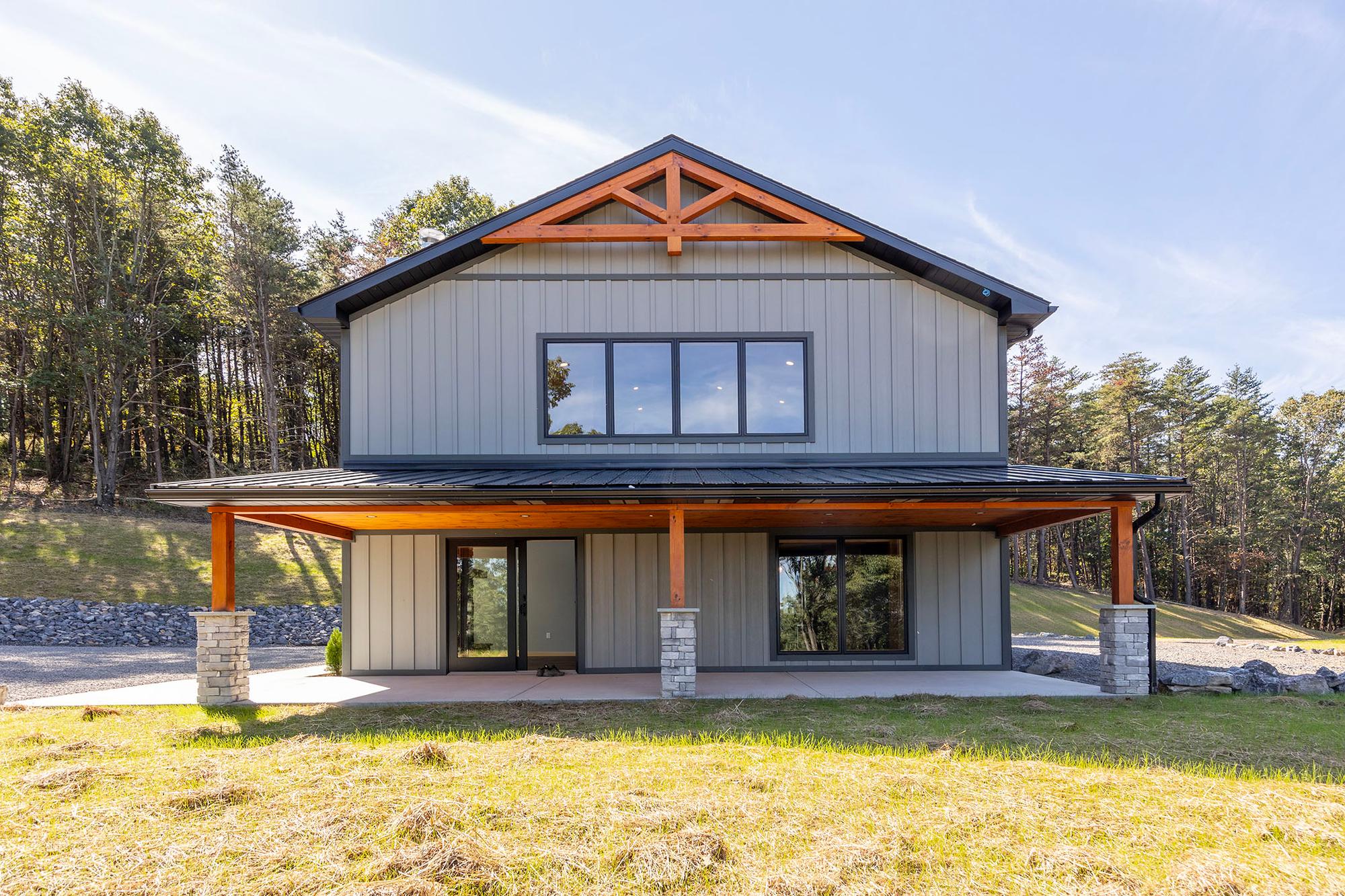 Gable end of the home with a timber king-post truss above a full-width covered patio carried on timber posts and stone piers
