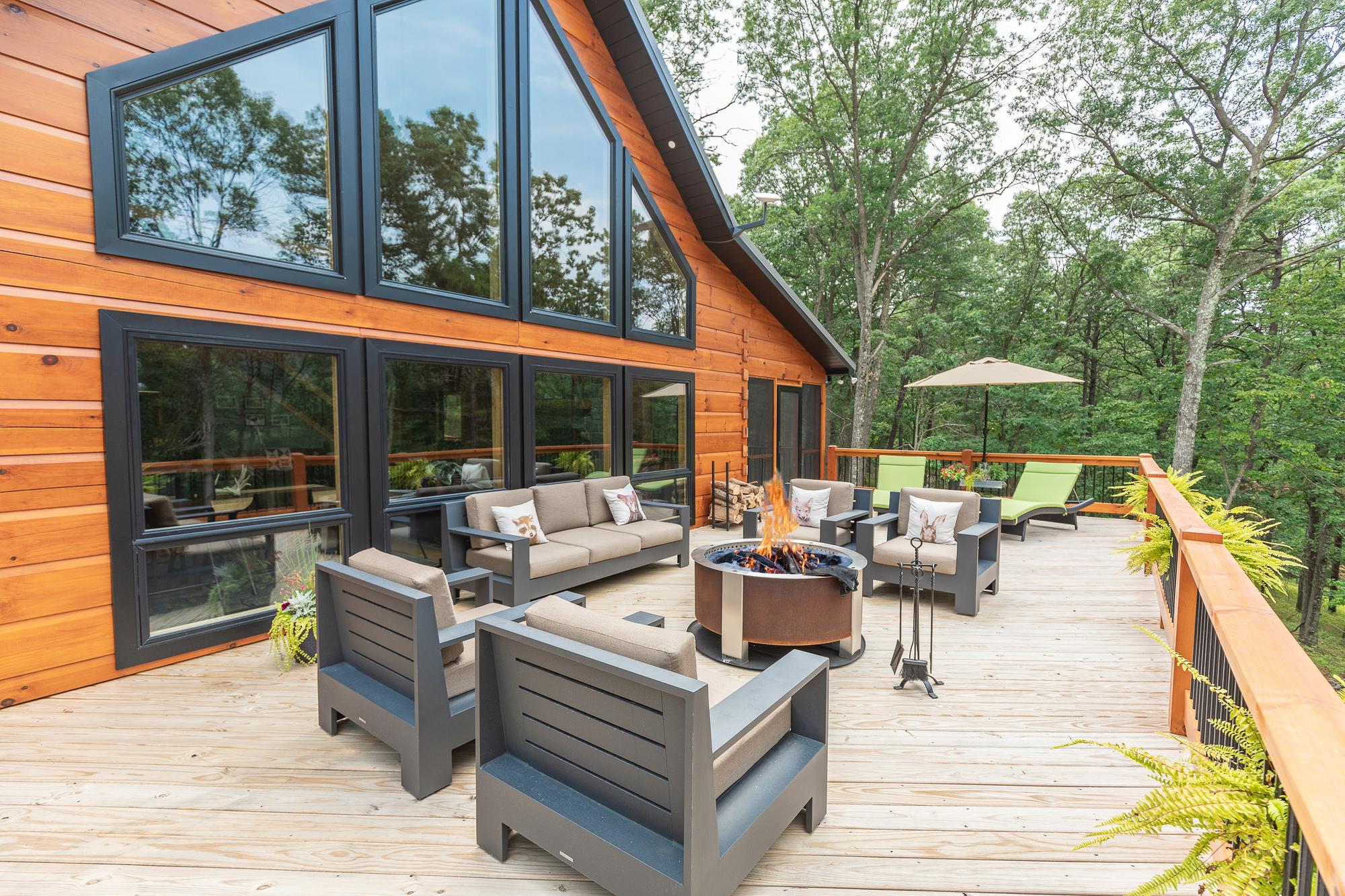 The gable window wall seen from the deck, with a lit fire pit and lounge seating in front