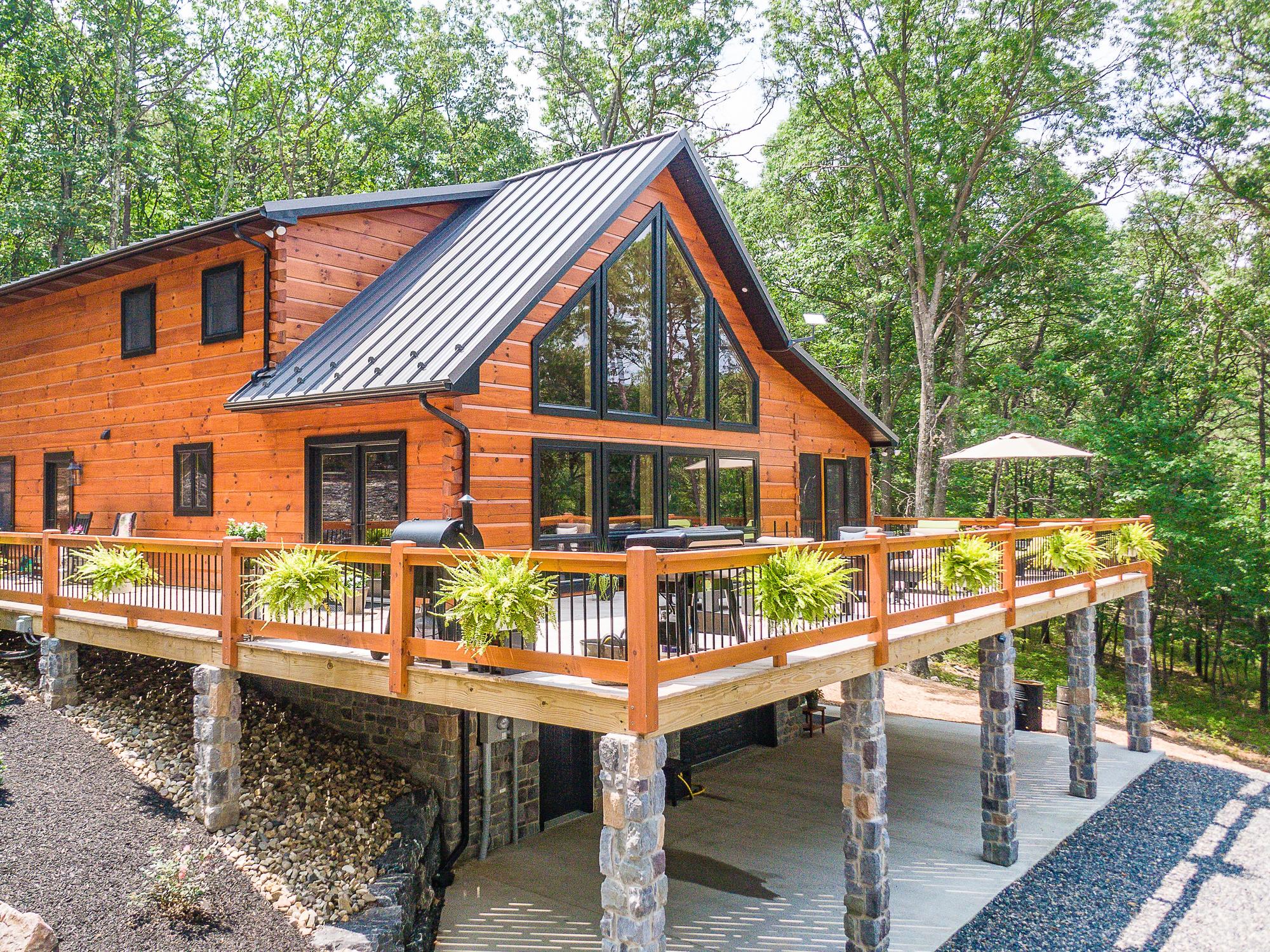 The log home and its deck from the air on a clear day, an open umbrella over the dining table