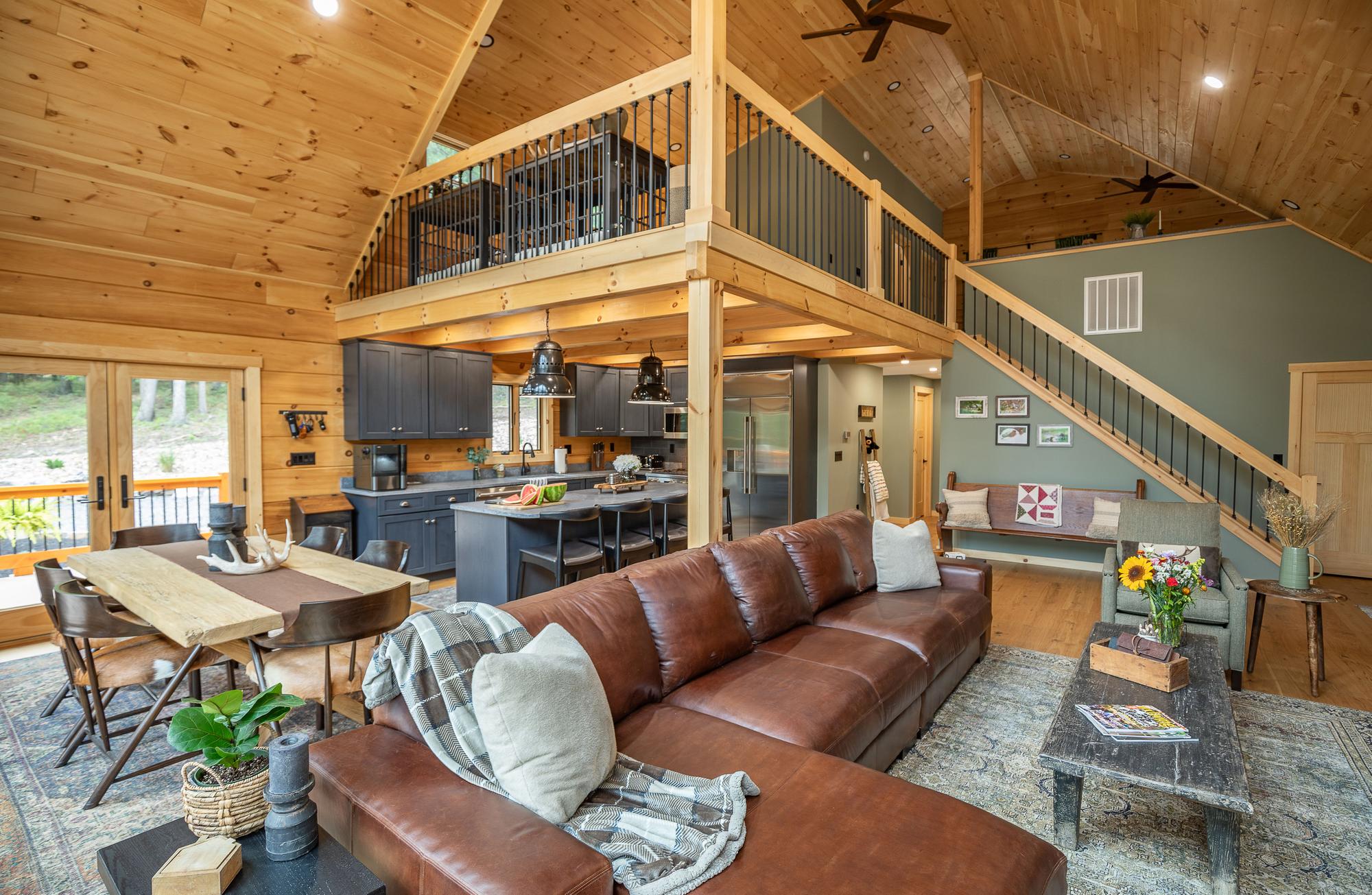 The open plan across the leather sectional, with the dining table, kitchen, stair and loft beyond