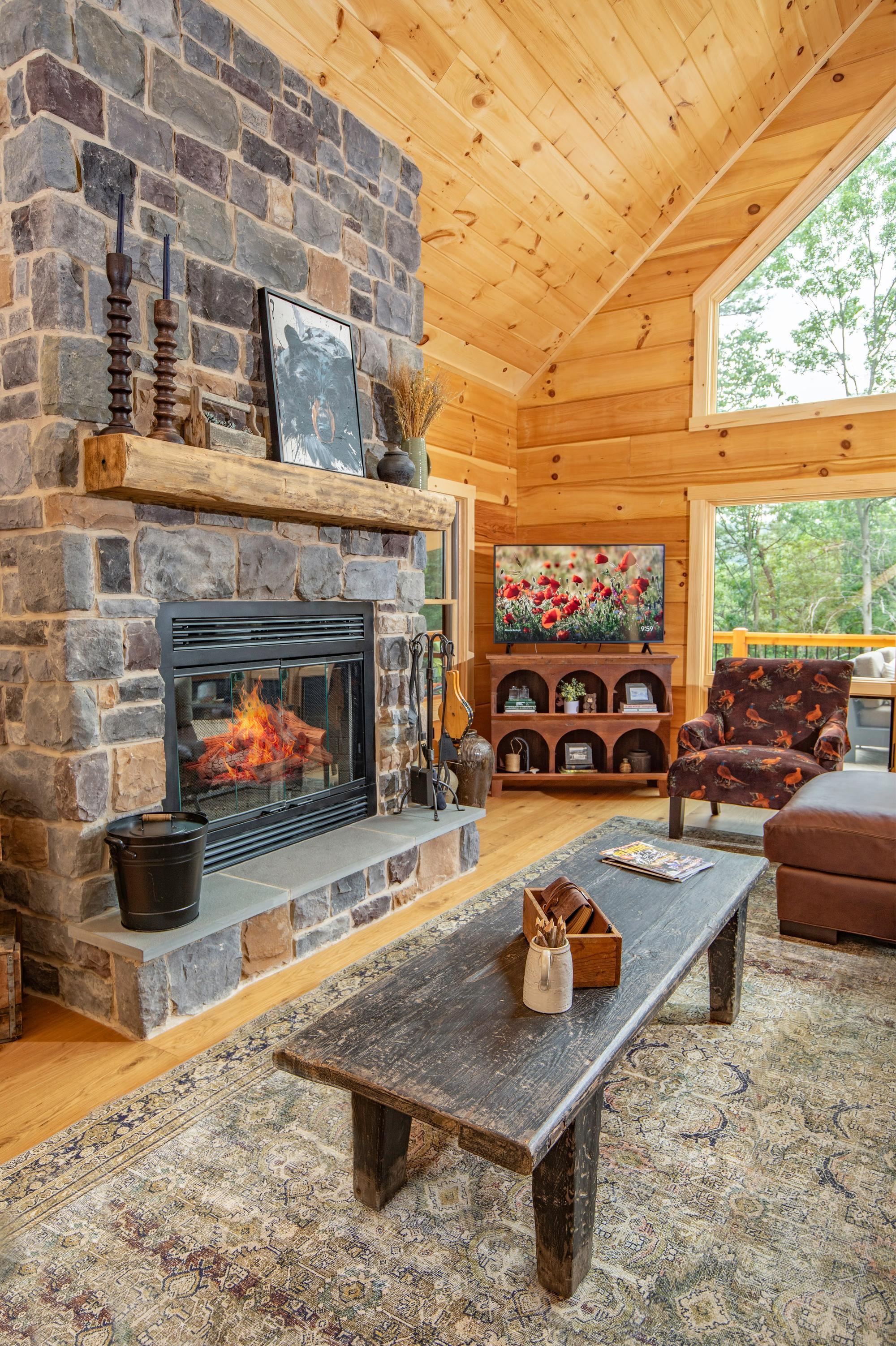 Stone fireplace with a lit fire, a patterned armchair beside it