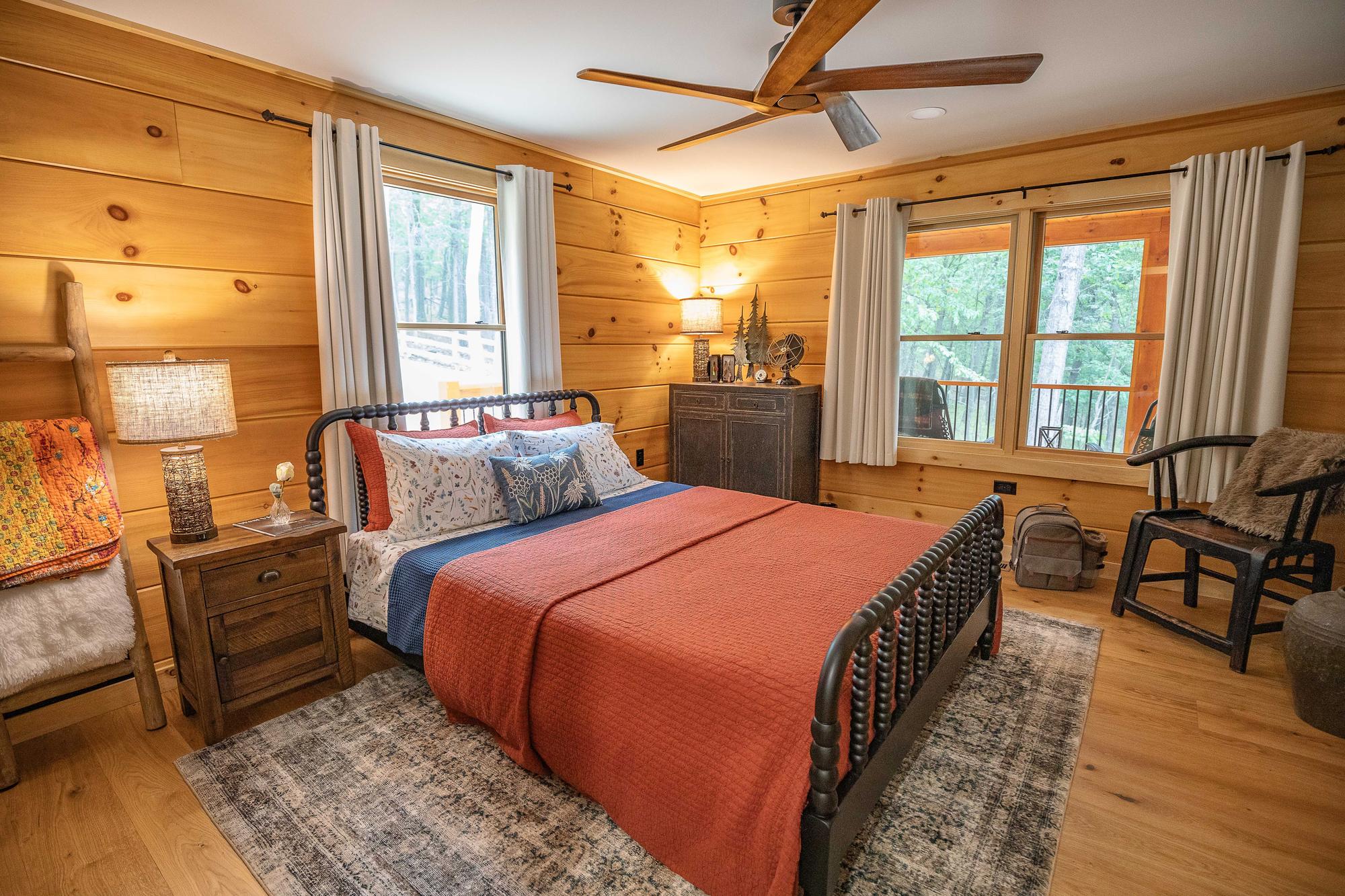 Guest bedroom with rust-colored bedding against wood-paneled walls