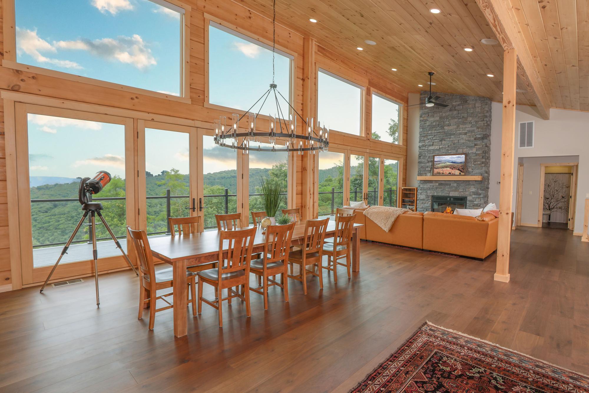 The great room and dining table from the far end, two stories of windows looking down the valley
