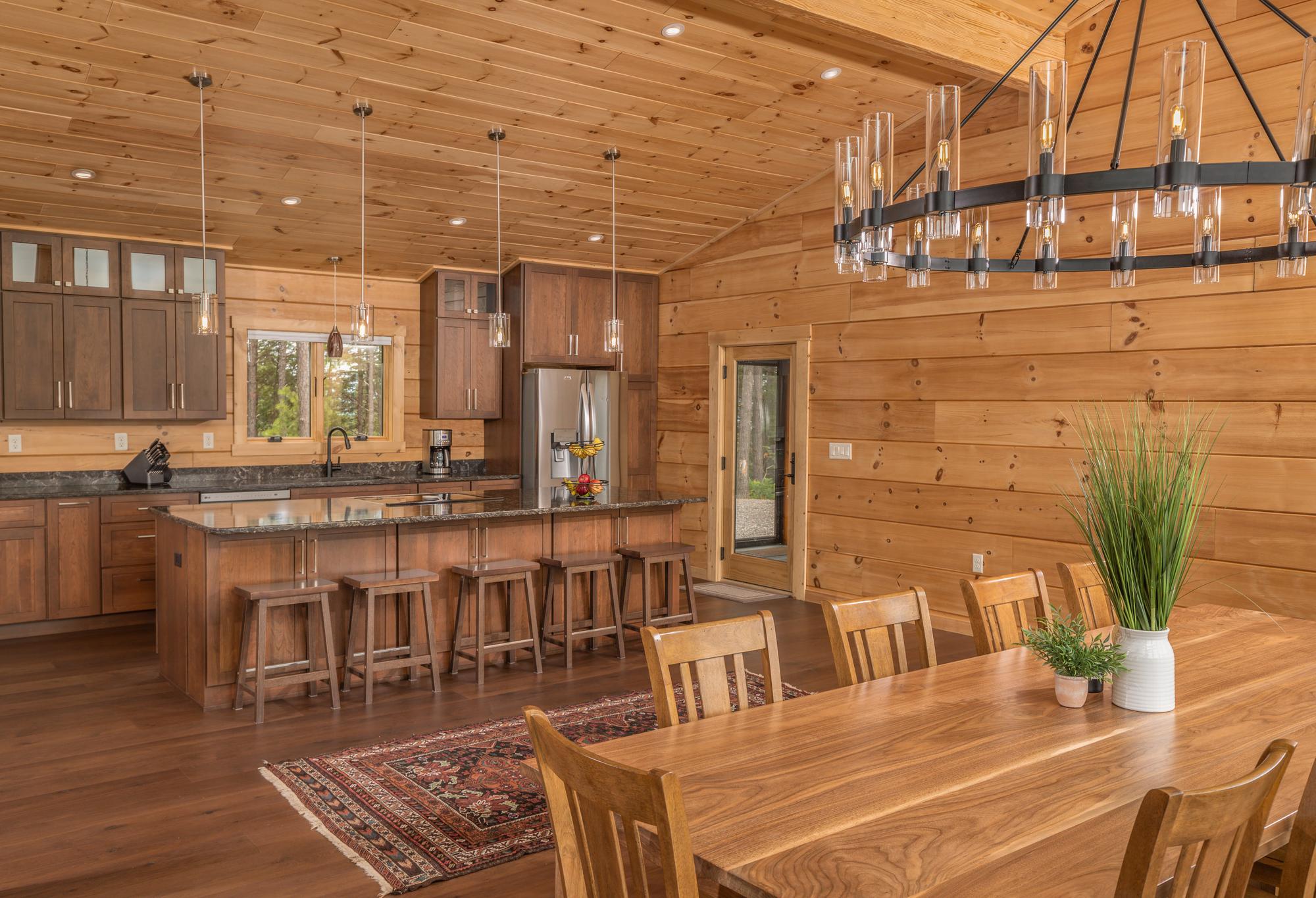 Kitchen with cherry cabinets, granite counters and a bar with wooden stools, the dining table alongside