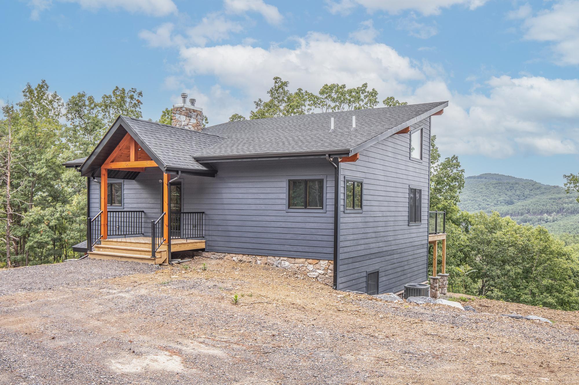 The same front elevation from further back, the roofline running down toward the walkout side