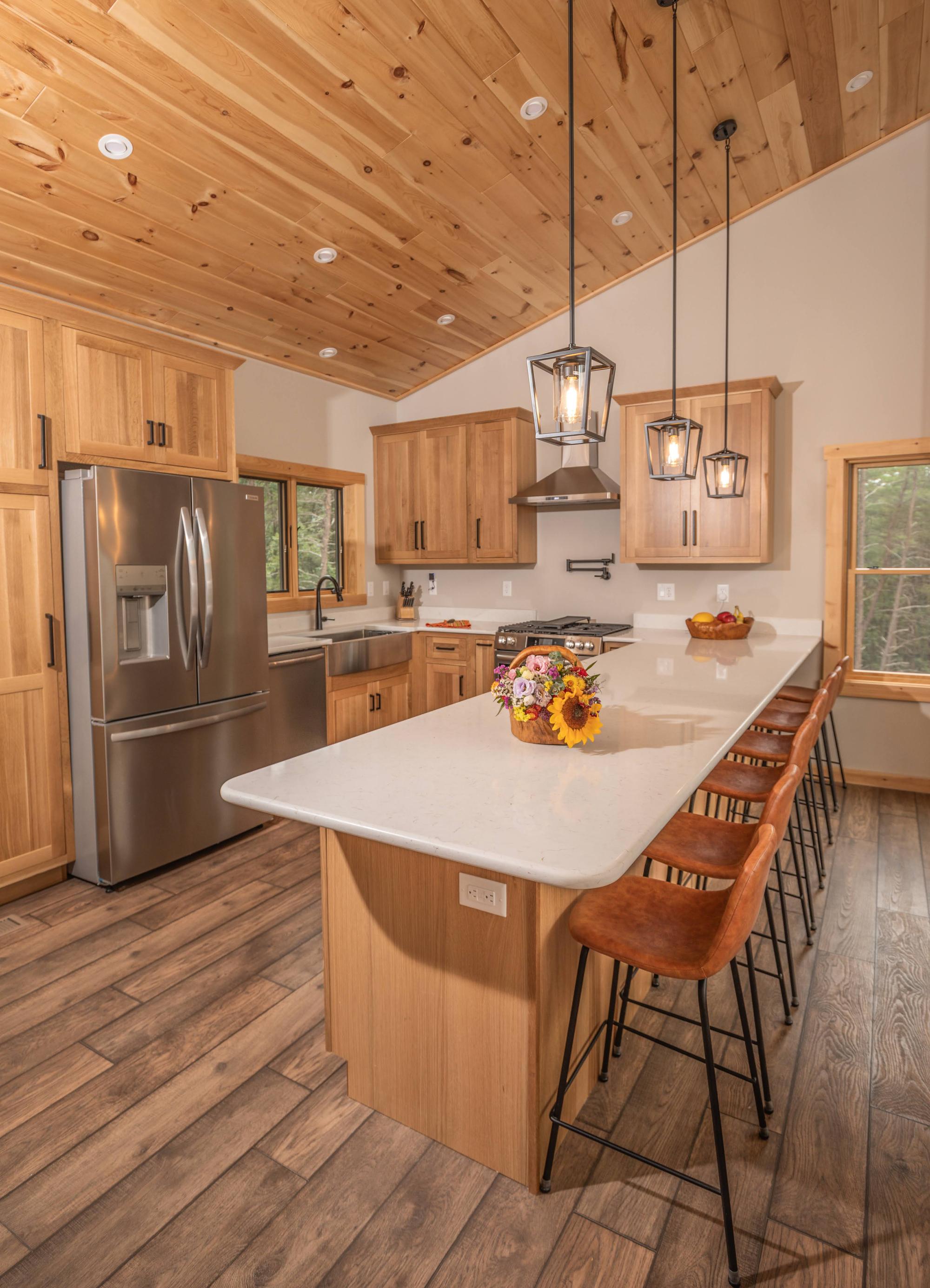 The kitchen along its length, showing the full quartz peninsula and the range wall beyond