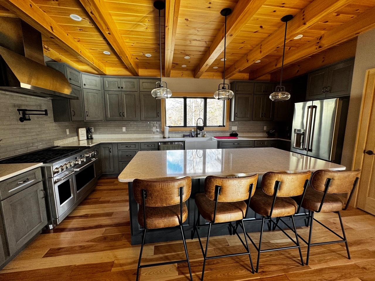 The kitchen from the range end, showing the professional range, pot filler and the island beyond