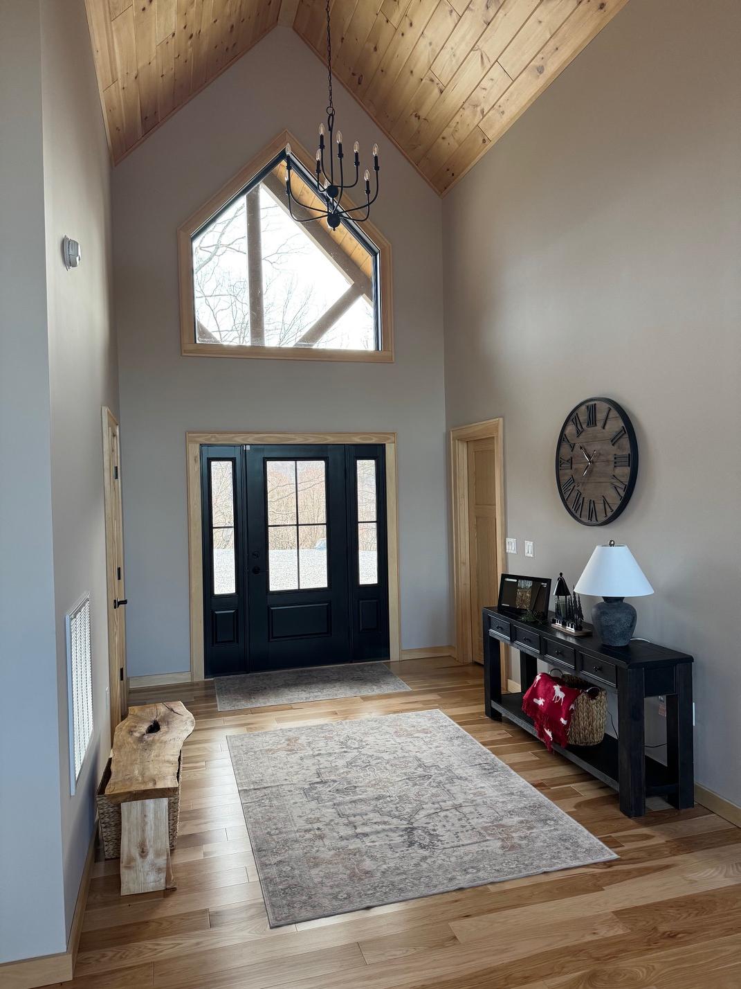 Two-story entry hall with a black double door, a gable window above and an iron chandelier