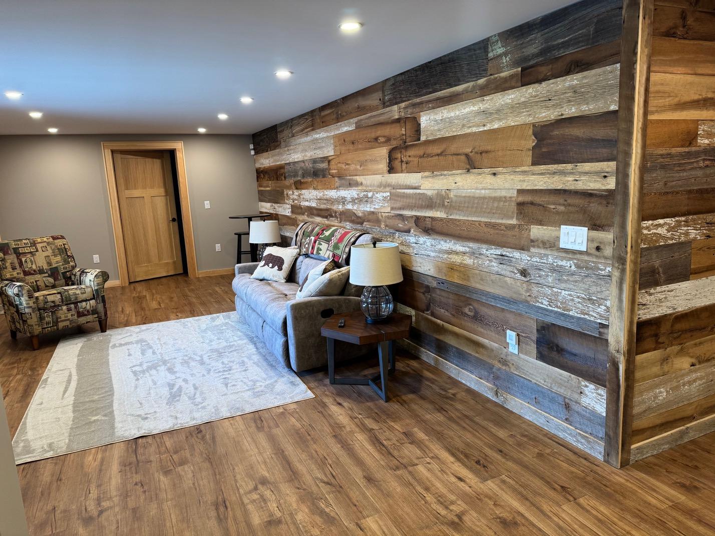 Lower-level lounge against a reclaimed barnwood wall, with a sofa, a recliner and table lamps