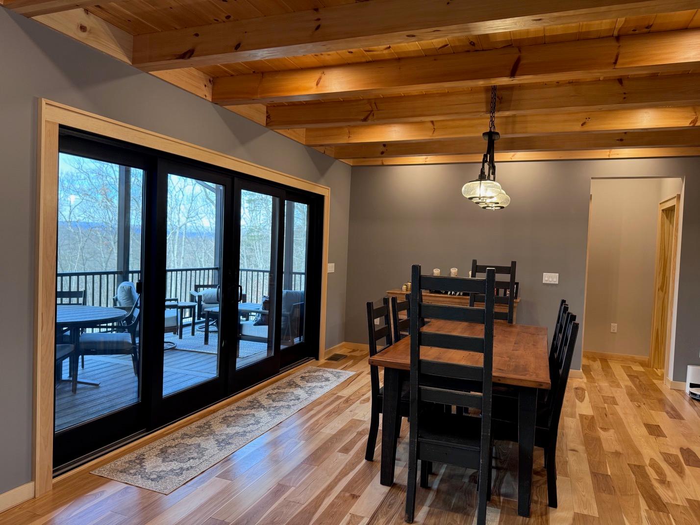 The dining area from the far side, a four-panel slider running the length of the wall out to the porch