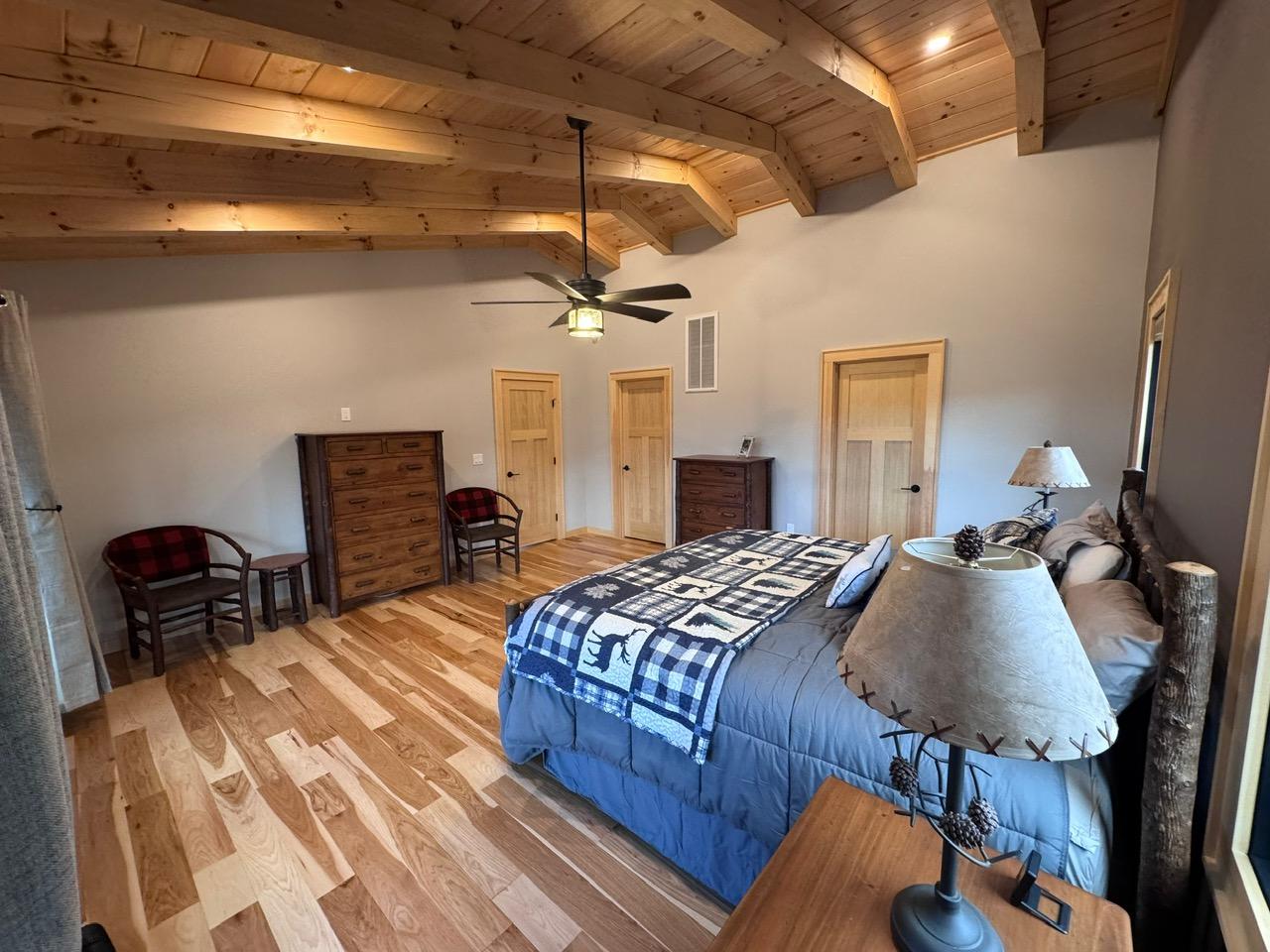 A second bedroom with a log bed, beamed ceiling and check-upholstered chairs