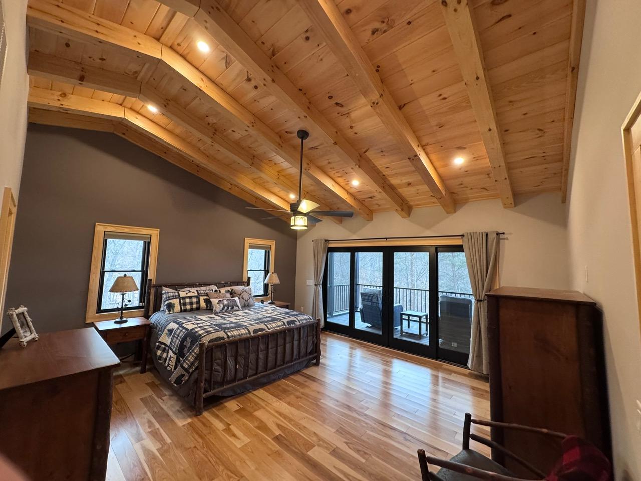 Main bedroom with a hickory log bed under a beamed pine ceiling, and French doors onto the deck