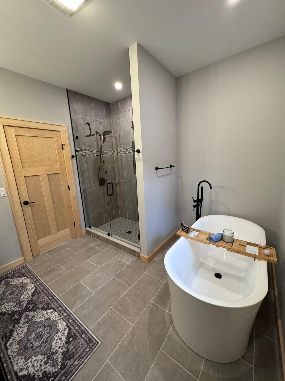 A second bathroom with a glass shower and a freestanding tub on gray tile