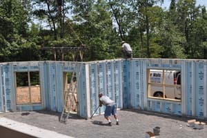 The basement enclosed on three sides, one of the crew bracing a panel below while another works on top of the wall.