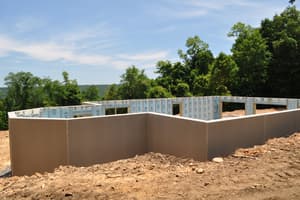 Precast foundation walls set in place on a hilltop, tan on the outside and blue insulation facing in, with ridgelines beyond.