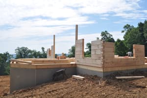 The first courses of log wall on the deck, square-cut timbers stacked two and three high, the valley in the distance.