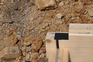 A log corner joint close up, black foam gasket tape along the top and a row of long lag bolts laid out ready on the boards below.