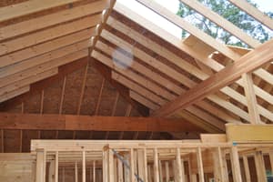 Roof framing seen from inside, rafters running up to the ridge, a heavy beam across the gable and stud walls of the level below.