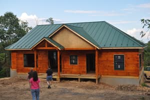The finished log exterior under a green standing-seam roof, with a covered front porch and visitors walking up to it.