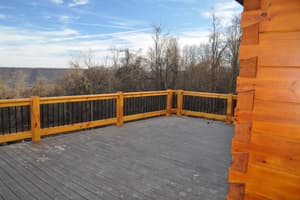 The deck, looking out over the valley through bare trees, a yellow rail across the front.