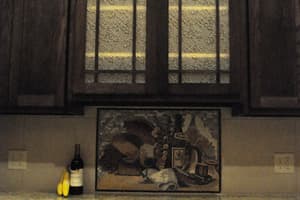 A kitchen range wall of dark-stained cabinets with a glass-paneled vent hood, a tile mosaic in the backsplash, and an oven below the granite.