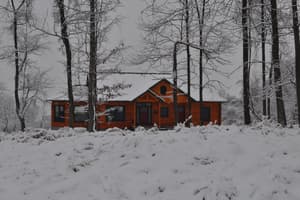 The finished house straight on in deep snow, green roof white with it, the ground unbroken in front.