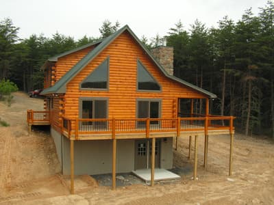 The home square on, gable of glass above the deck and a stone chimney beside it