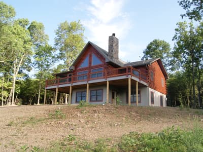 The home square on across rough ground, gable glass centered over a full-width deck on posts