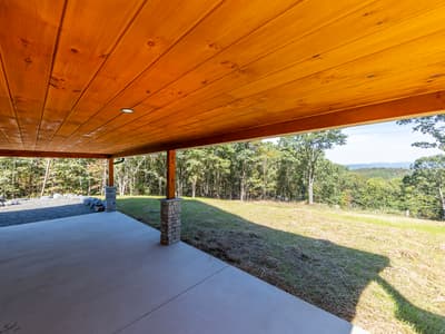 View from under the covered patio across a grass slope to forested ridges in the distance