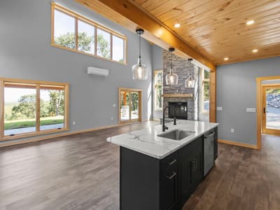 Kitchen island in the foreground with the stacked-stone fireplace beyond and windows onto the covered patio and lawn