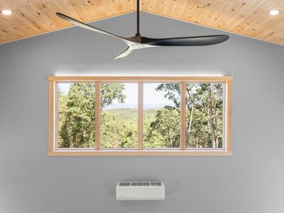 Four-pane window framing treetops and distant ridges under the peak of the pine ceiling, a mini-split centered below