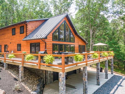The log home and its deck from the air on a clear day, an open umbrella over the dining table