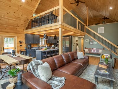 The open plan across the leather sectional, with the dining table, kitchen, stair and loft beyond