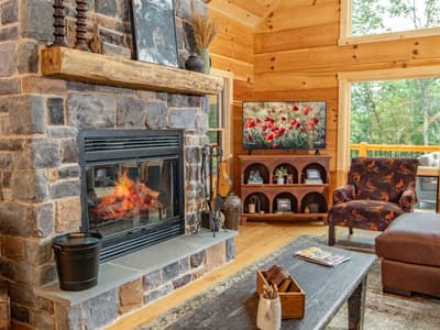 Stone fireplace with a lit fire, a patterned armchair beside it