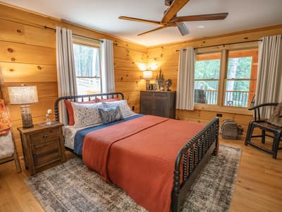 Guest bedroom with rust-colored bedding against wood-paneled walls