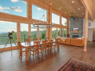 The great room and dining table from the far end, two stories of windows looking down the valley