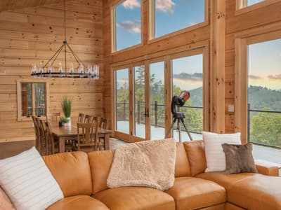 The sectional facing the window wall, with the dining table behind and a telescope beside the deck doors