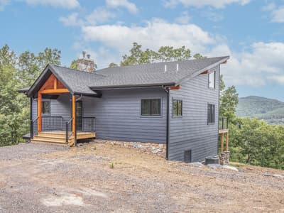 The same front elevation from further back, the roofline running down toward the walkout side