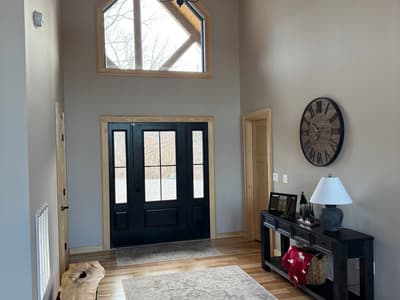Two-story entry hall with a black double door, a gable window above and an iron chandelier