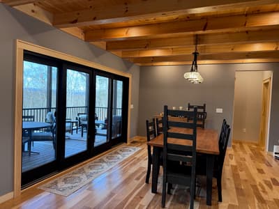 The dining area from the far side, a four-panel slider running the length of the wall out to the porch