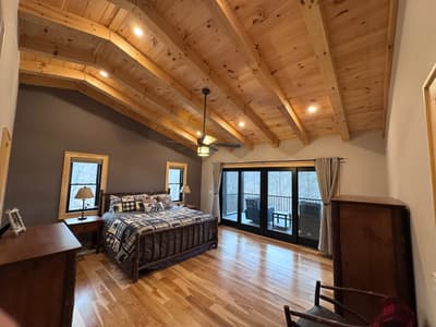 Main bedroom with a hickory log bed under a beamed pine ceiling, and French doors onto the deck
