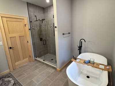 A second bathroom with a glass shower and a freestanding tub on gray tile