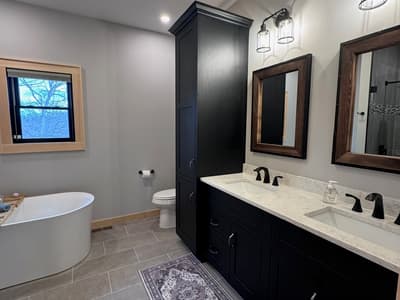 Main bathroom with a black double vanity, wood-framed mirrors and lantern sconces
