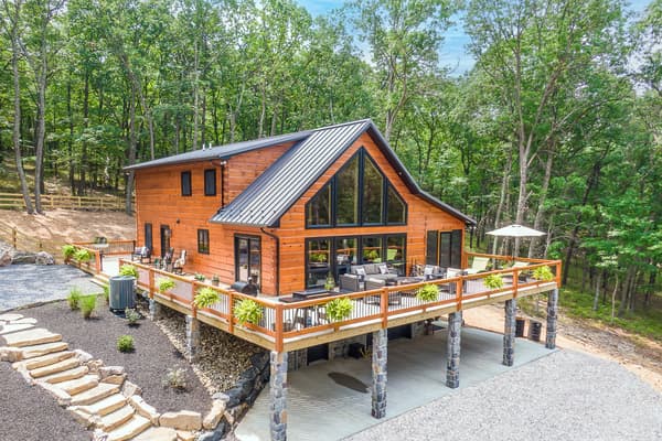 A full log home with a wraparound deck and metal roof in the West Virginia hills