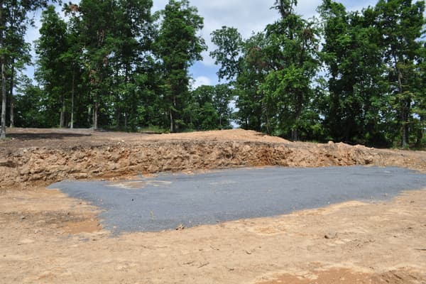 A rectangle of gray gravel laid on the graded pad, the footprint of the house marked out on bare orange dirt.
