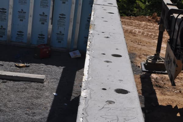 A single precast panel hanging level on its lifting straps, the insulated face and cast-in studs visible along its back.